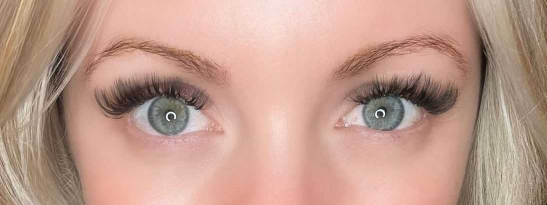 Close-up of a person's blue eyes with long, thick eyelashes.